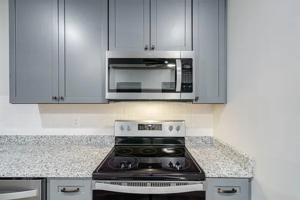a kitchen with granite countertop stainless steel appliances a stove a microwave and cabinets