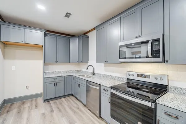 a kitchen with granite countertop a sink stainless steel appliances and cabinets