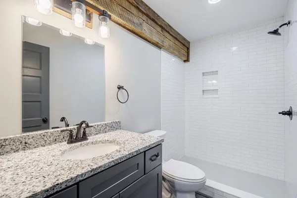 a bathroom with a granite countertop sink a toilet and a mirror