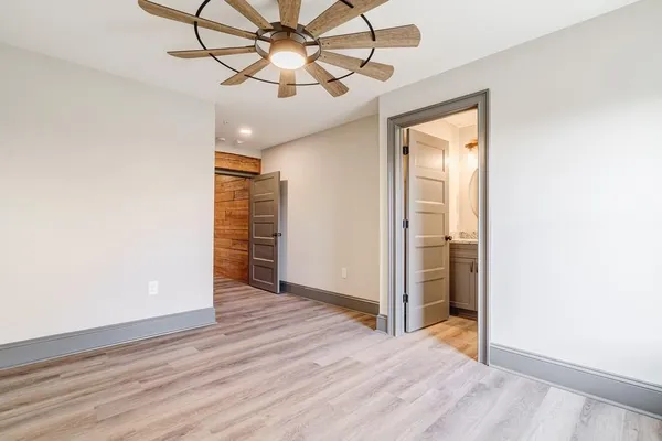 an empty room with wooden floor chandelier fan and closet area