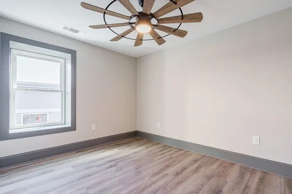 a view of empty room with wooden floor and fan