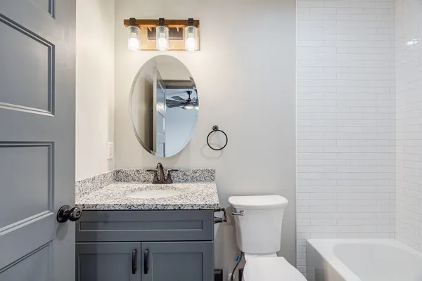a bathroom with a toilet sink vanity and mirror