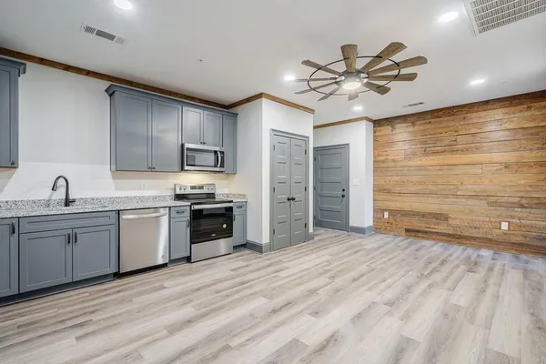 a kitchen with stainless steel appliances granite countertop a sink cabinets and wooden floor