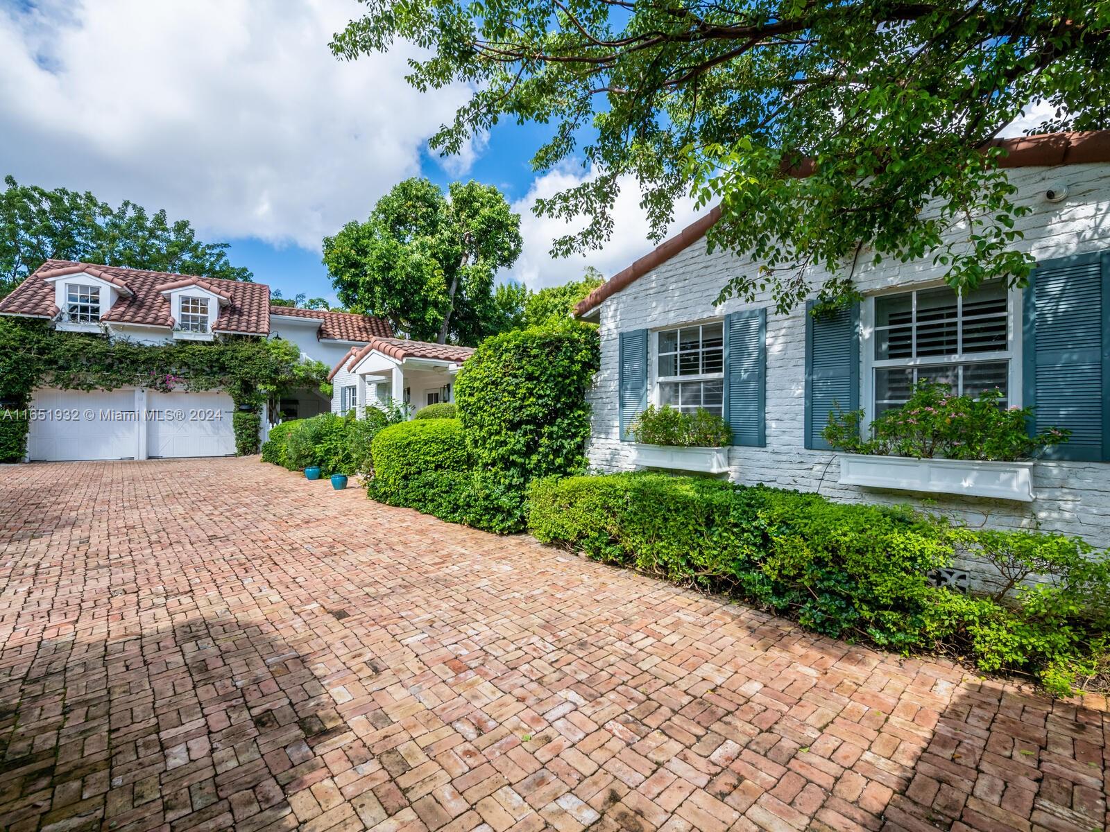 a front view of a house with a yard and potted plants