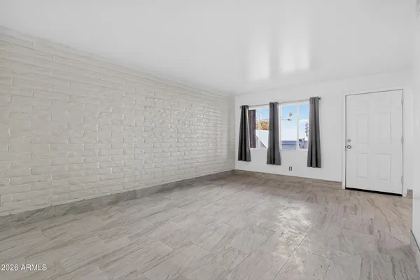 a view of an empty room with wooden floor and windows