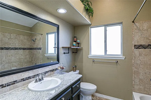 a bathroom with a granite countertop sink a toilet and a mirror