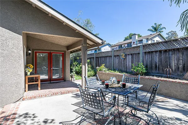 a view of a patio with table and chairs potted plants and floor to ceiling window