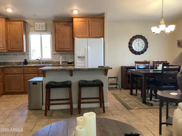 a kitchen with kitchen island granite countertop a sink a stove a dining table and chairs