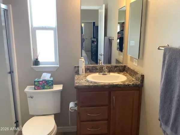 a bathroom with a granite countertop toilet sink and mirror