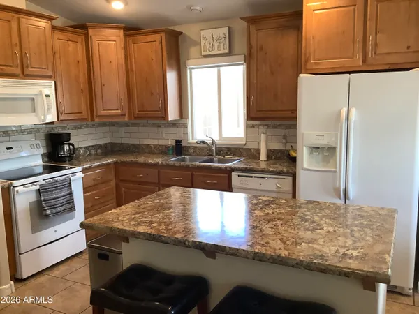 a kitchen with kitchen island granite countertop a sink stove and refrigerator
