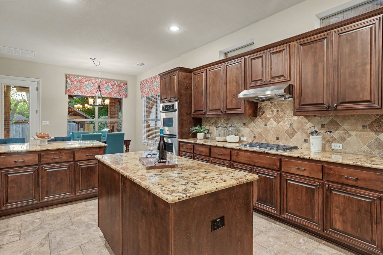 2828 Collingwood Drive Round Rock, TX 78665 - Photo 12 of 38 a kitchen with kitchen island granite countertop wooden cabinets a sink and dishwasher