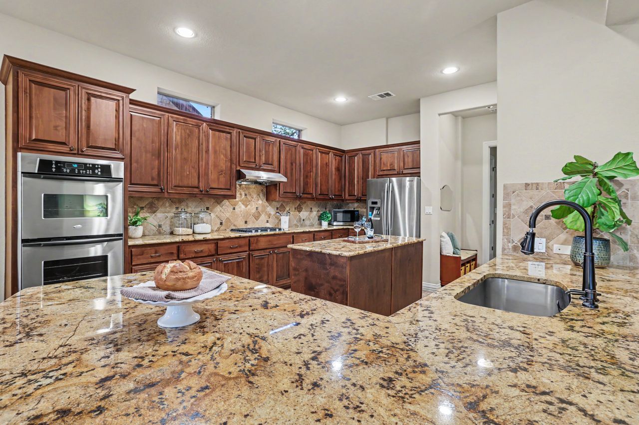 2828 Collingwood Drive Round Rock, TX 78665 - Photo 14 of 38 a kitchen with a stove a sink and a refrigerator with wooden cabinets