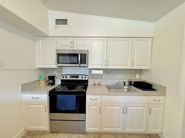 a kitchen with white cabinets and black appliances