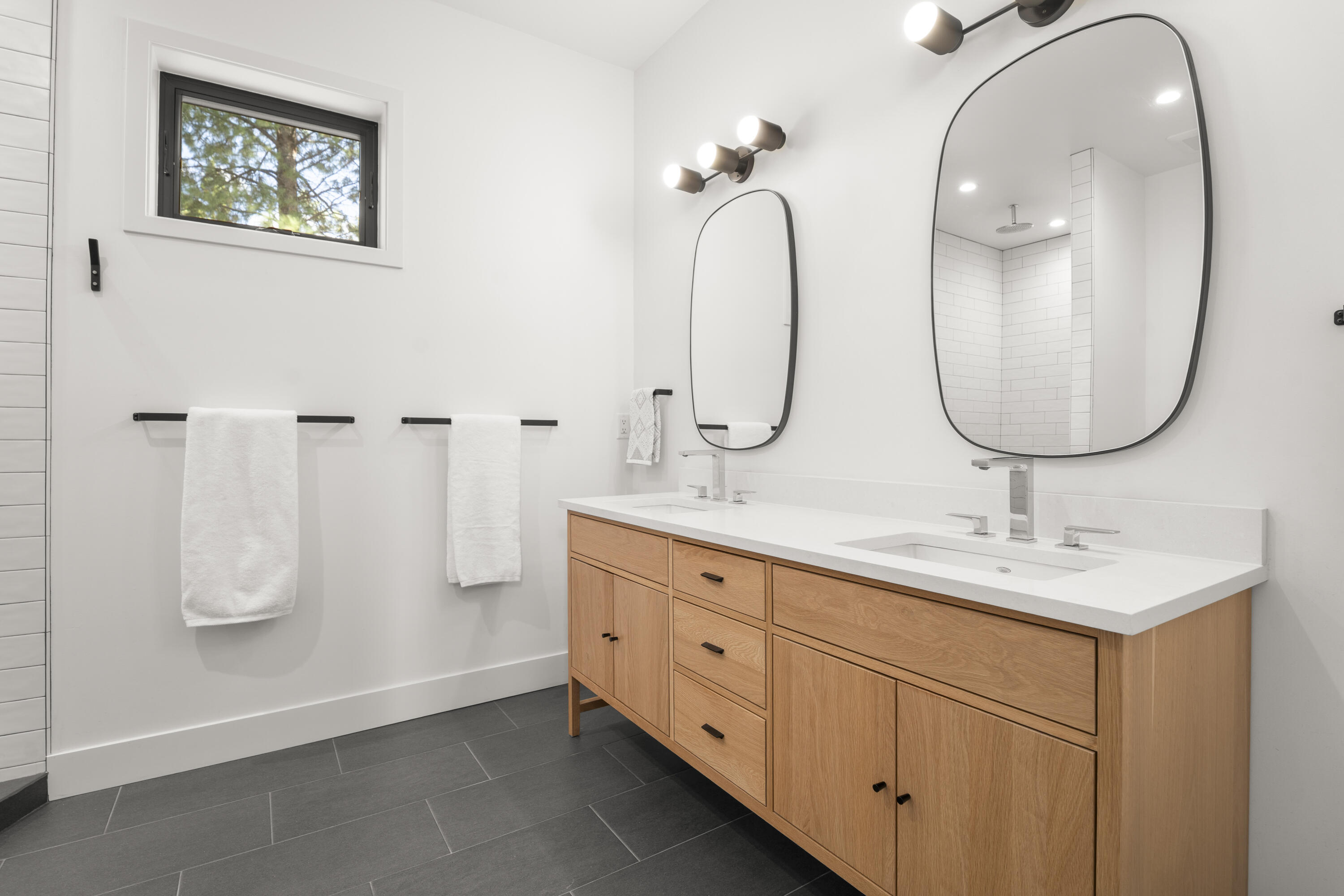 56670 Sunstone Loop, Unit LOT 141 Bend, OR 97707 - Photo 5 of 62 The primary bath blends warmth and simplicity with a double vanity, quartz-style counters, modern lighting, and natural wood cabinetry. The large walk-in shower with full-height tile and built-in bench creates a bright, polished retreat.