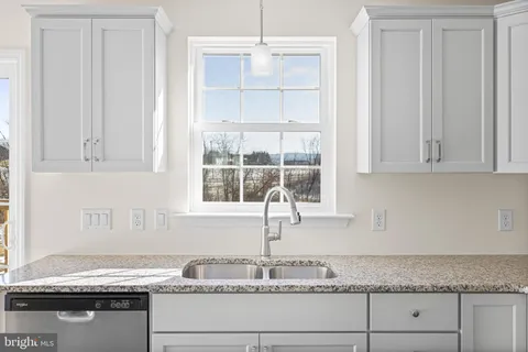 a kitchen with granite countertop white cabinets and a window