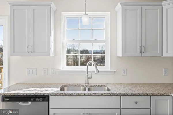 a kitchen with granite countertop white cabinets and a window