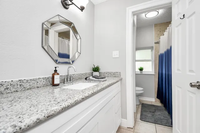 a bathroom with a granite countertop toilet sink and mirror