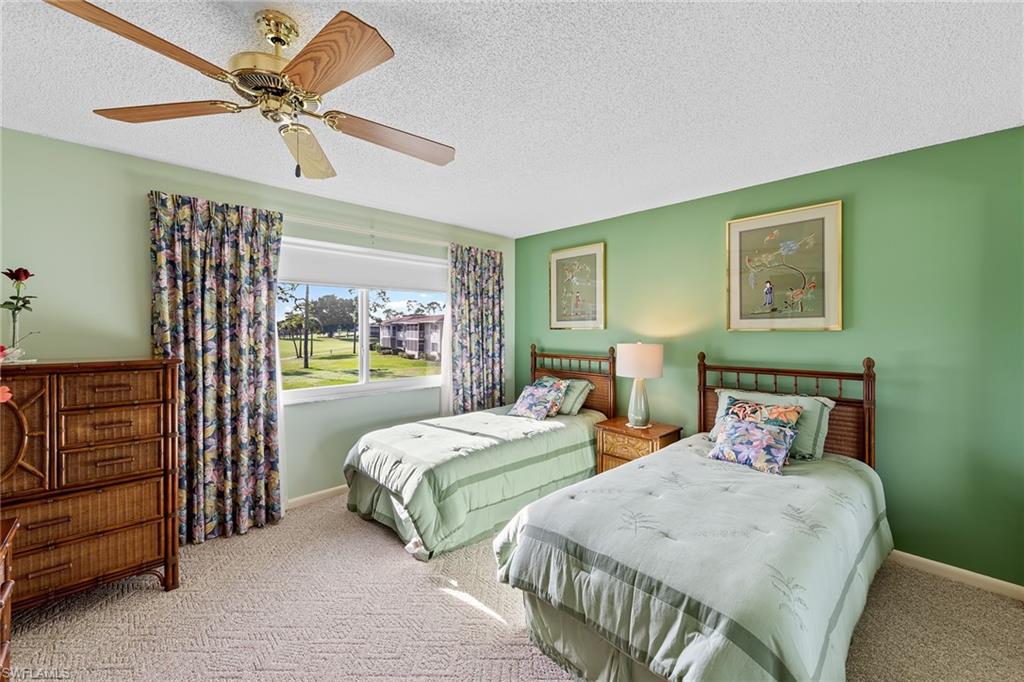 200 Albi Road, Unit 2 Naples, FL 34112 - Photo 28 of 49 a bedroom with two beds and a chandelier