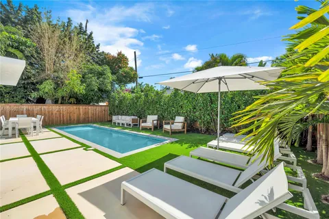 a view of a backyard with chairs and an umbrella