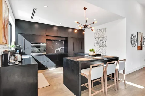 a kitchen with stainless steel appliances kitchen island granite countertop a table chairs in it and wooden floors