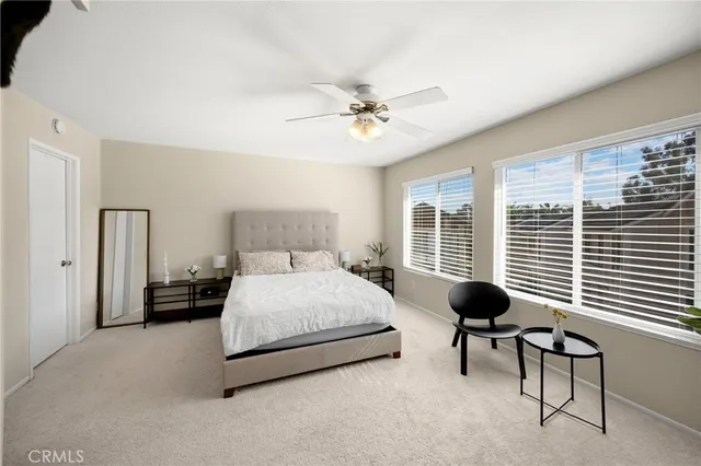 a bedroom with a bed a chair and a large window