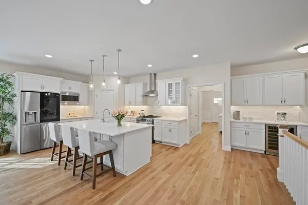 a large kitchen with cabinets wooden floor stainless steel appliances and dining table
