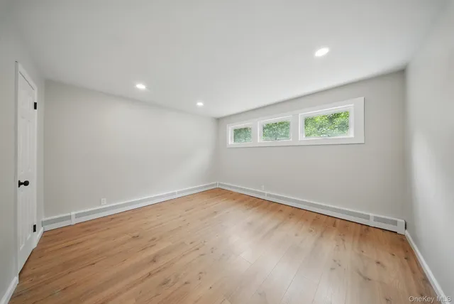 an empty room with wooden floor and window