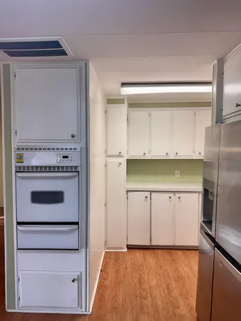 a kitchen with white cabinets and refrigerator