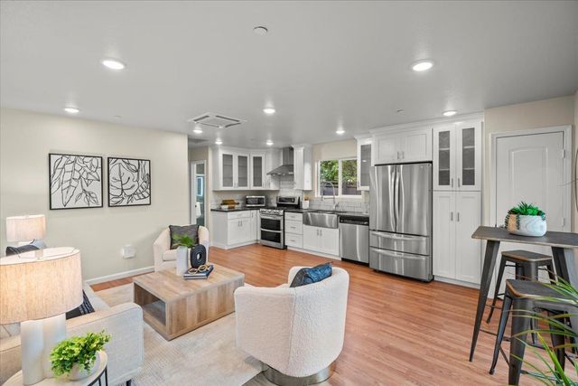 a living room with stainless steel appliances kitchen island granite countertop furniture wooden floor and a kitchen view