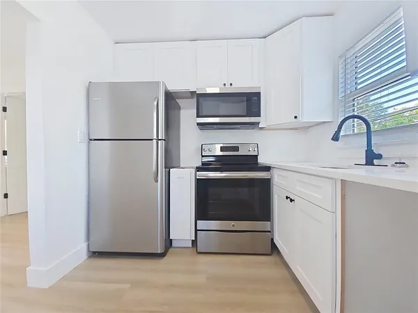 a kitchen with a refrigerator sink and white cabinets