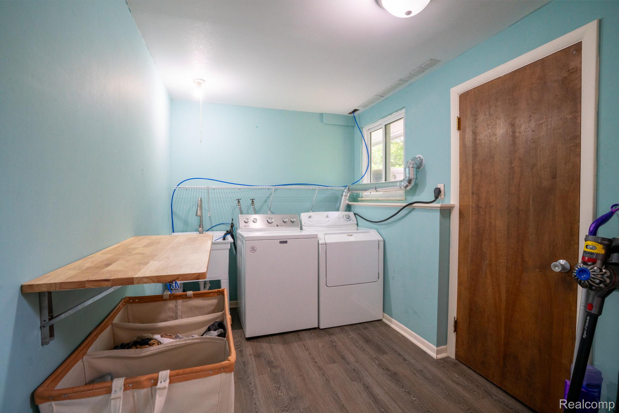 7333 Toma Road Dexter, MI 48130 - Photo 38 of 45 Dedicated laundry space featuring a built-in folding table, utility sink, window, and wood-finish flooring