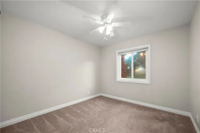 an empty room with a window and a fan