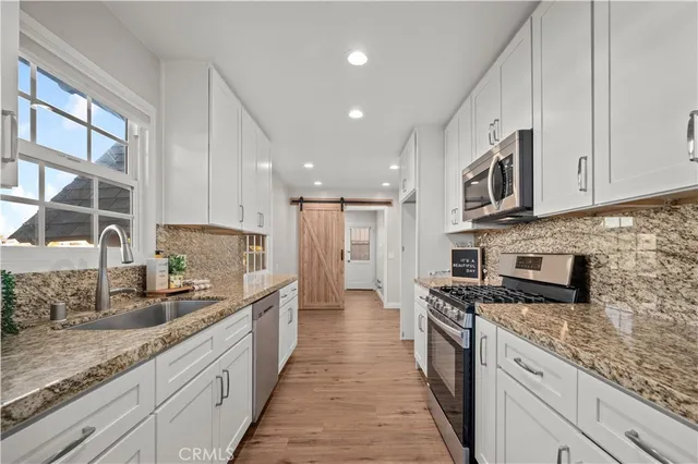a large kitchen with stainless steel appliances granite countertop a stove a sink and a granite counter tops