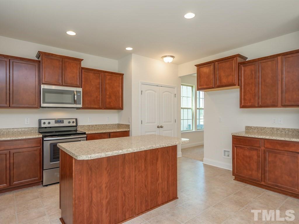 a kitchen with stainless steel appliances granite countertop a stove a sink a microwave a refrigerator and cabinets