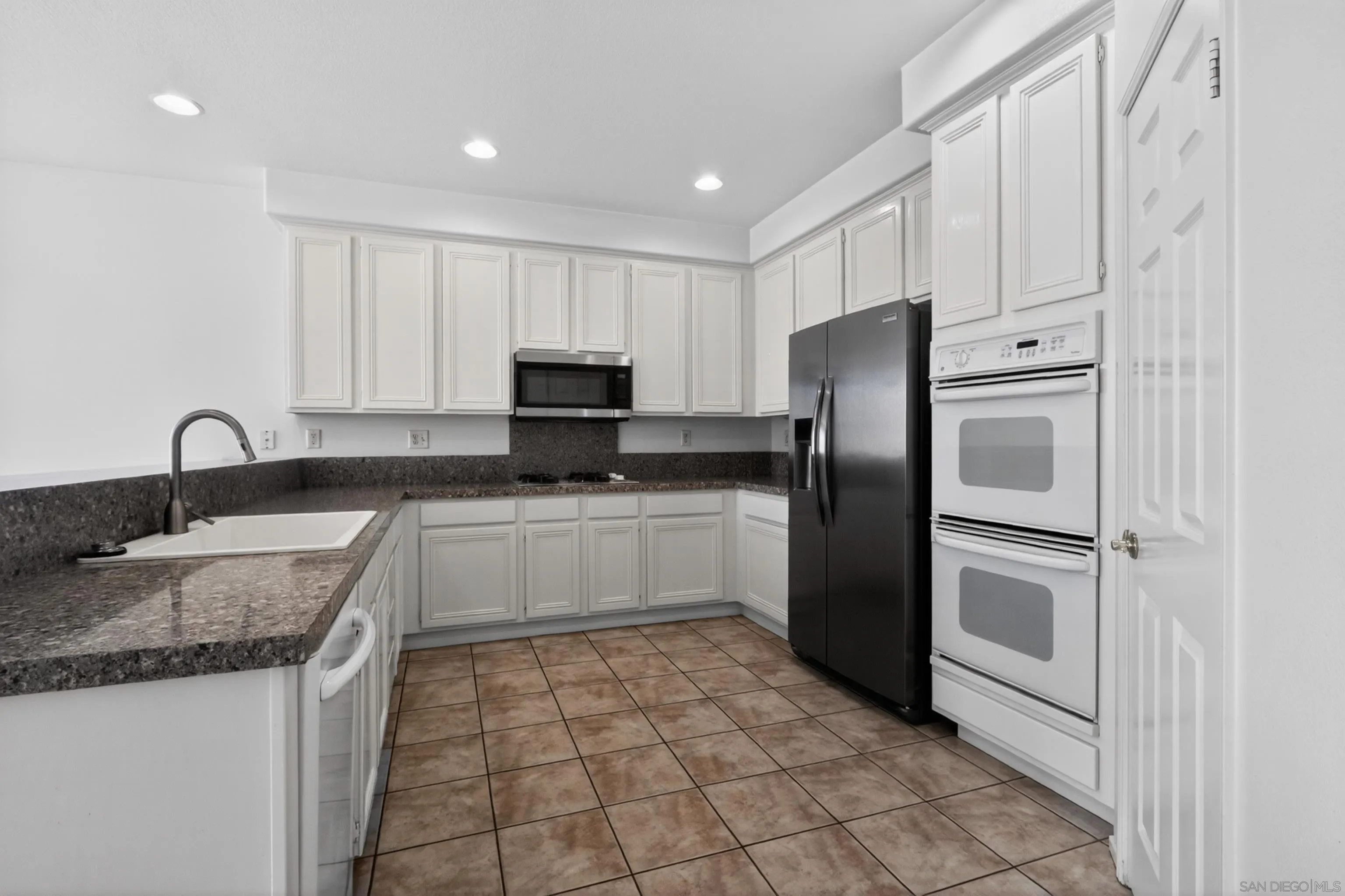 1432 Belmont Park Road Oceanside, CA 92057 - Photo 20 of 54 a kitchen with granite countertop a refrigerator sink and cabinets