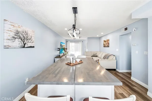 a kitchen with cabinets a sink dishwasher a stove and a dining table with wooden floor