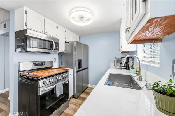 a kitchen with stainless steel appliances white cabinets and a window