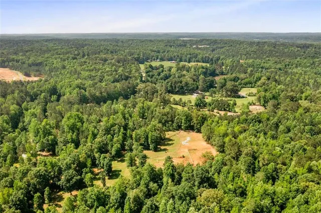 an aerial view of residential houses with outdoor space and trees