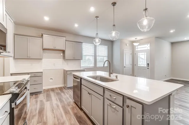 a kitchen with a sink a center island a stove cabinets and a wooden floors