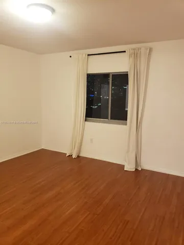 an empty room with wooden floor and entrance