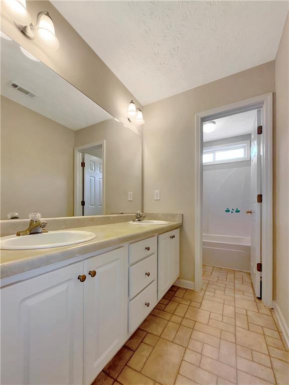 235 Shiver Boulevard Covington, GA 30016 - Photo 22 of 27 a spacious bathroom with a granite countertop sink a toilet mirror and a bathtub