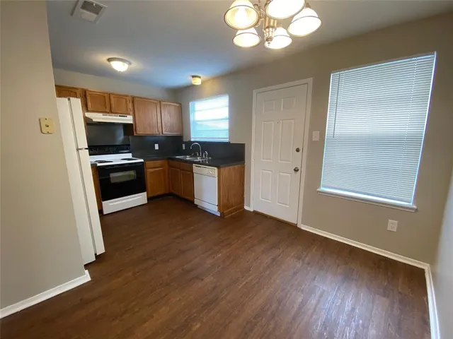 a kitchen with stainless steel appliances granite countertop a refrigerator a stove top oven a sink and dishwasher with wooden floor