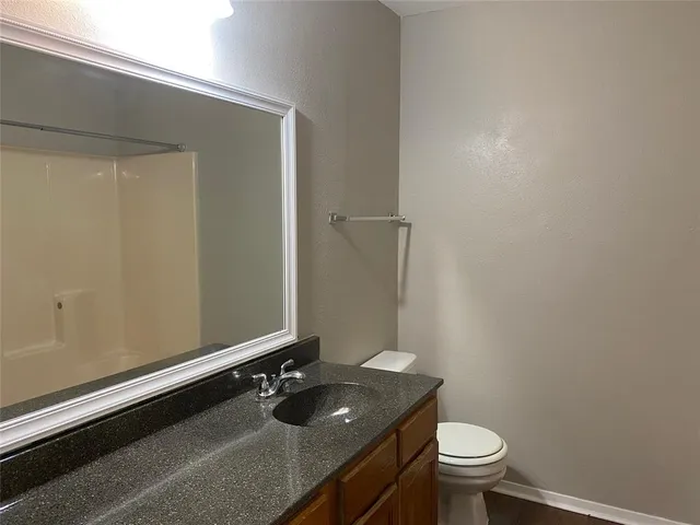 a bathroom with a granite countertop sink toilet and a mirror