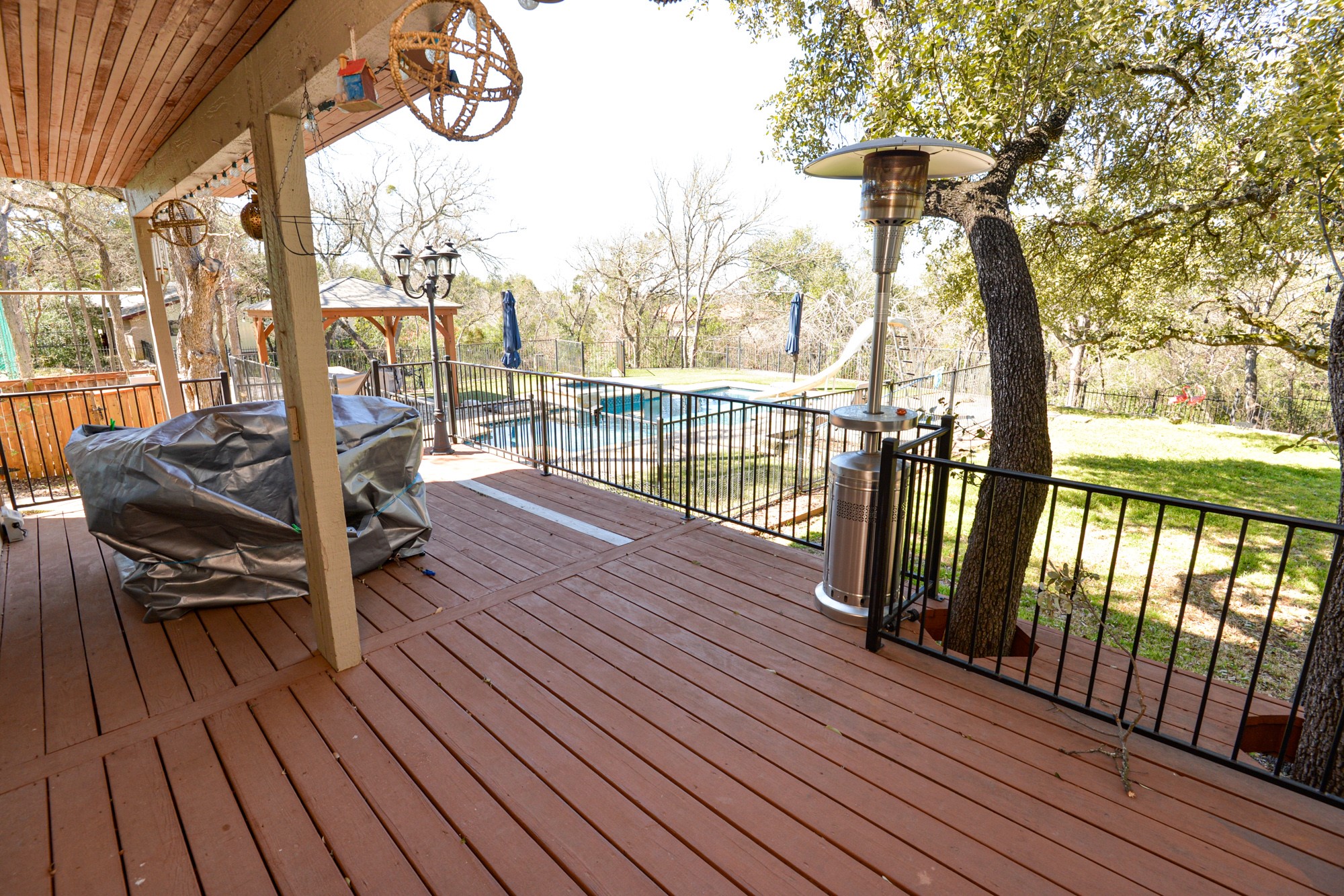 10710 D-K Ranch Road Austin, TX 78759 - Photo 2 of 34 A spacious wooden deck provides ample outdoor living space, overlooking a refreshing pool and verdant landscape.