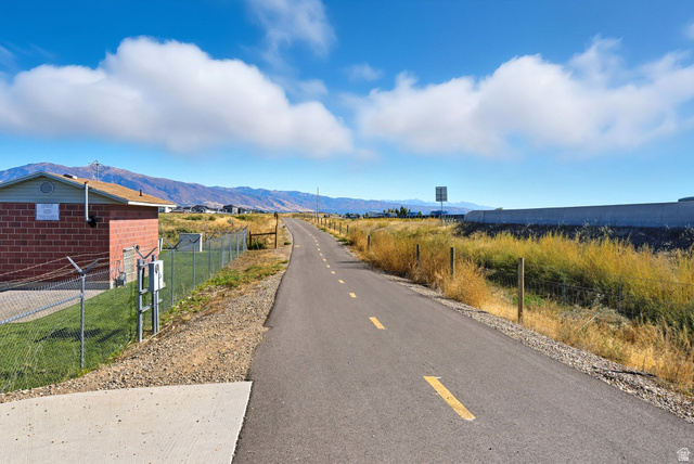 1278 South Grace Way Layton, UT 84041 - Photo 23 of 23 Paved pathway bordered by natural landscaping, featuring distant mountains and a clear sky backdrop