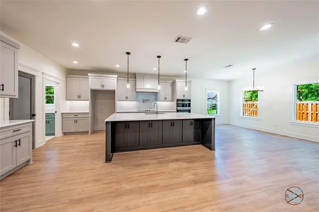 a large kitchen with kitchen island a sink wooden floor and a counter top space