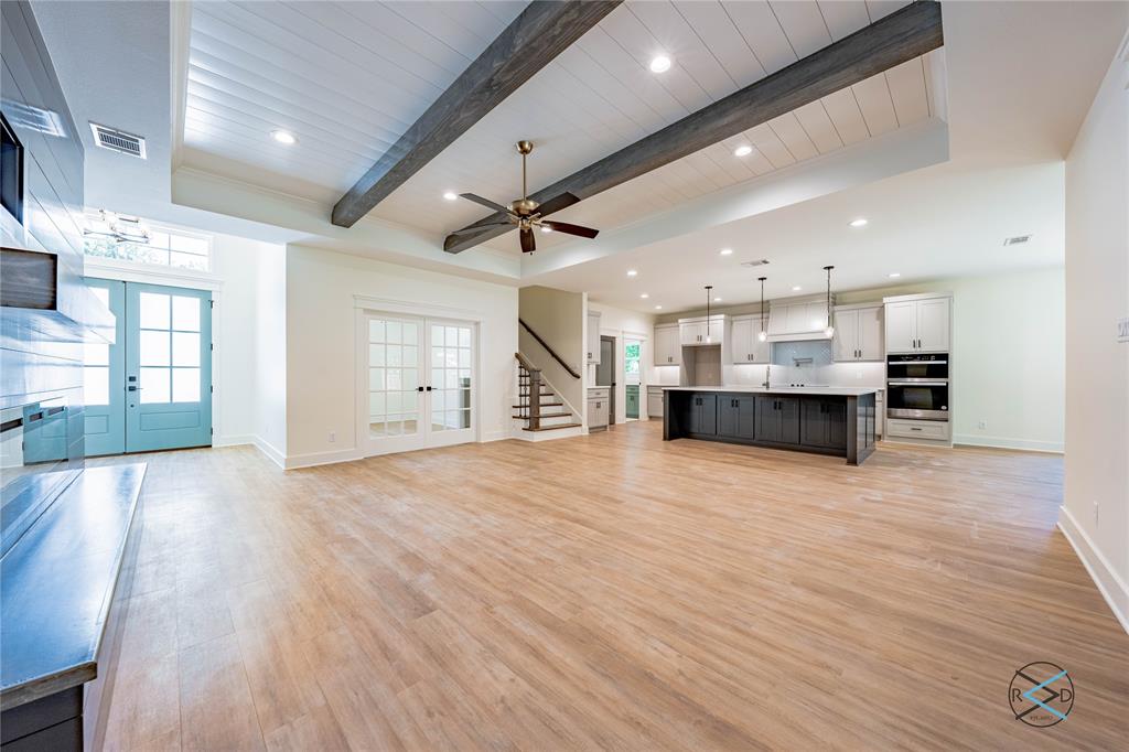 114 Castlewood Road Enchanted Oaks, TX 75156 - Photo 6 of 24 a view of an empty room and kitchen with window wooden floor and a kitchen