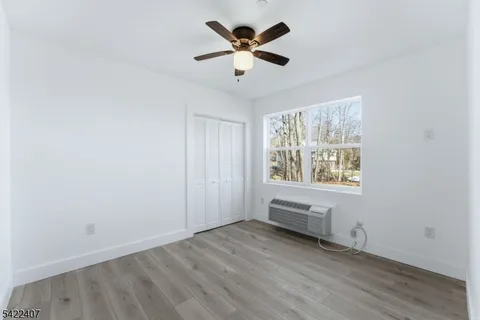 an empty room with chandelier fan and windows