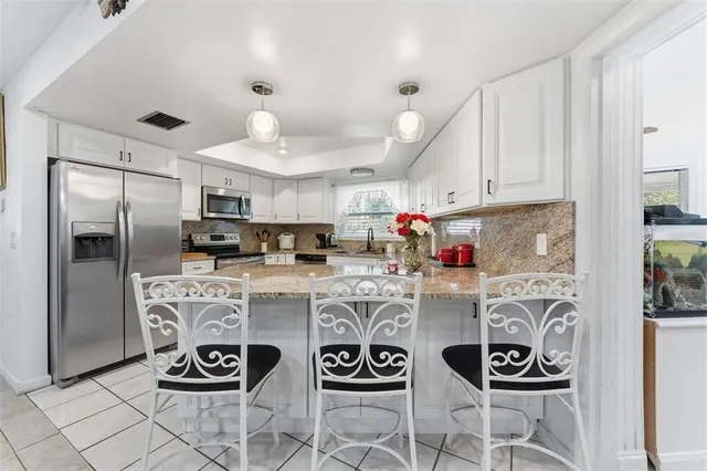 a kitchen with stainless steel appliances granite countertop a refrigerator and a stove top oven