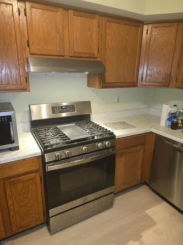 a kitchen with granite countertop cabinets stainless steel appliances and wooden floor